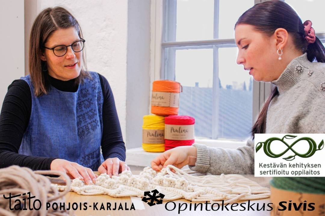 Kaksi naista pöydän ääressä tarkastelemassa neuletyötä.