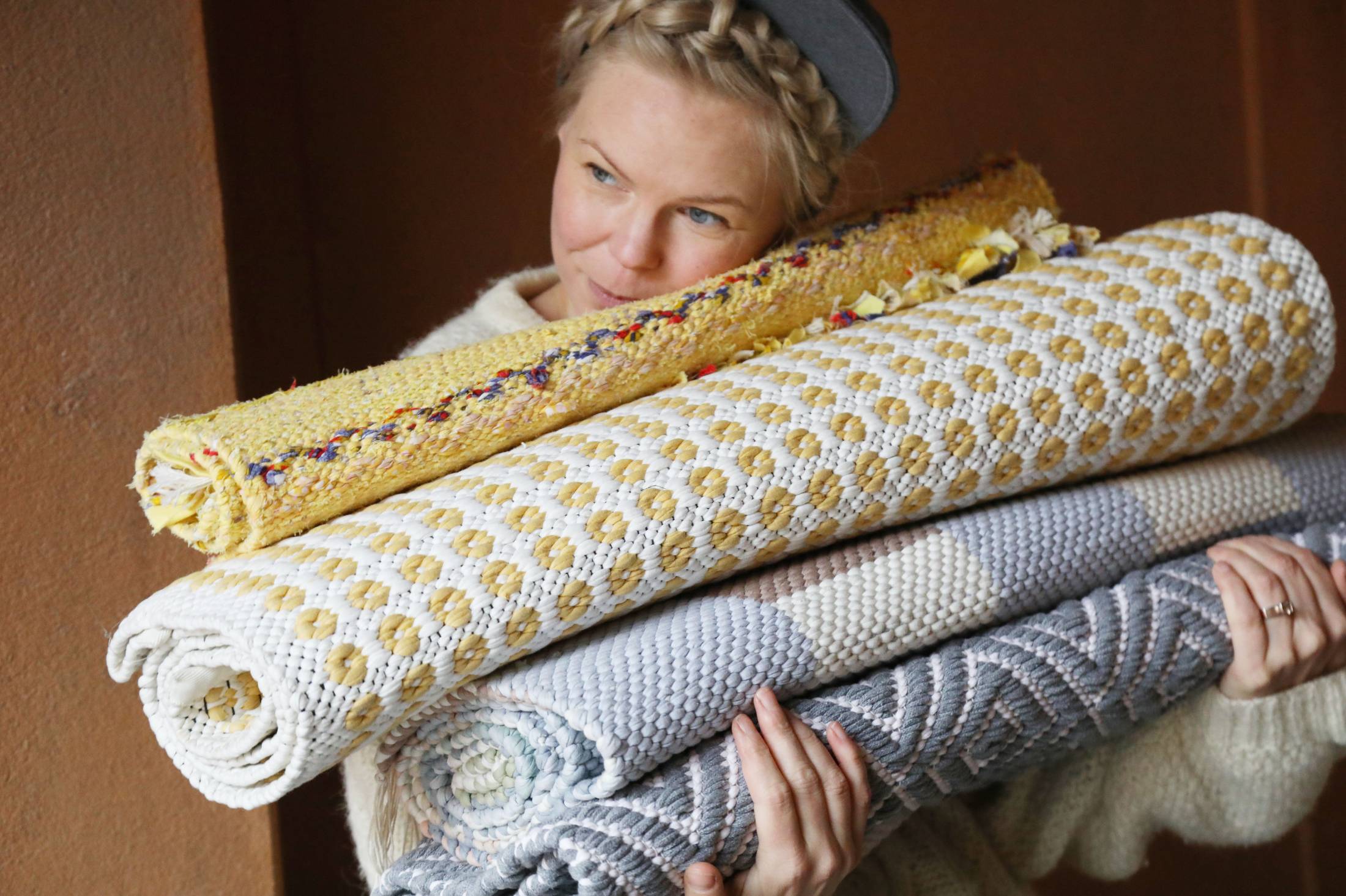 Nainen syleilemässä kudottuja mattoja