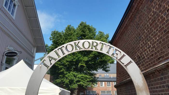 Taitokorttelin porttikaari kesäisessä miljöössä