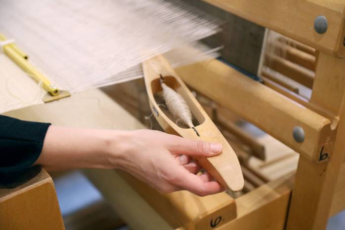 Kutova käsi työntää sukkulaa kangaspuiden viriöön