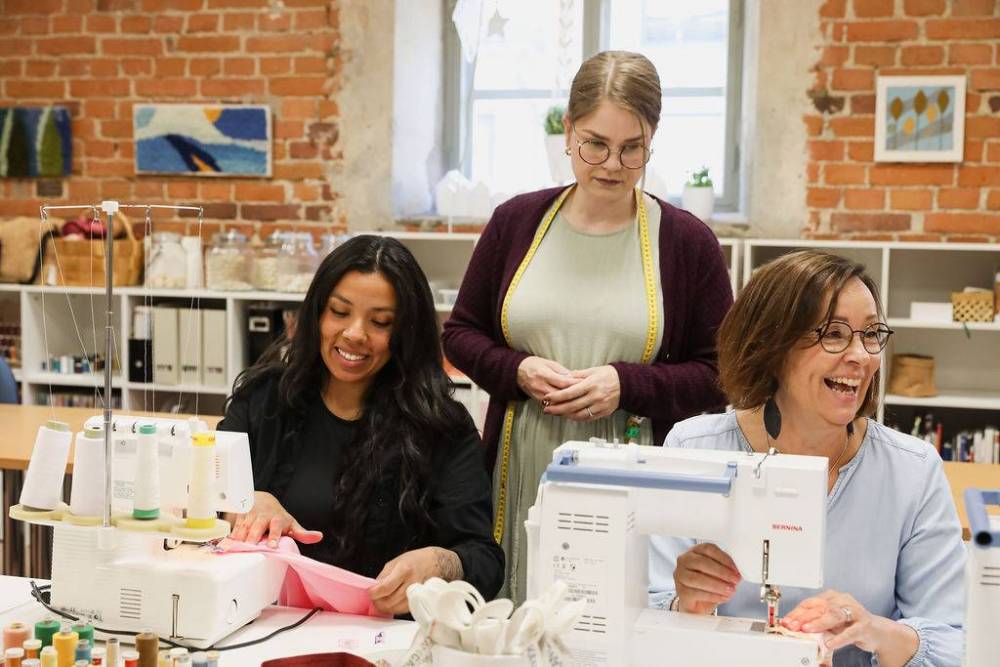 Three happy women sewing on a sewing machine